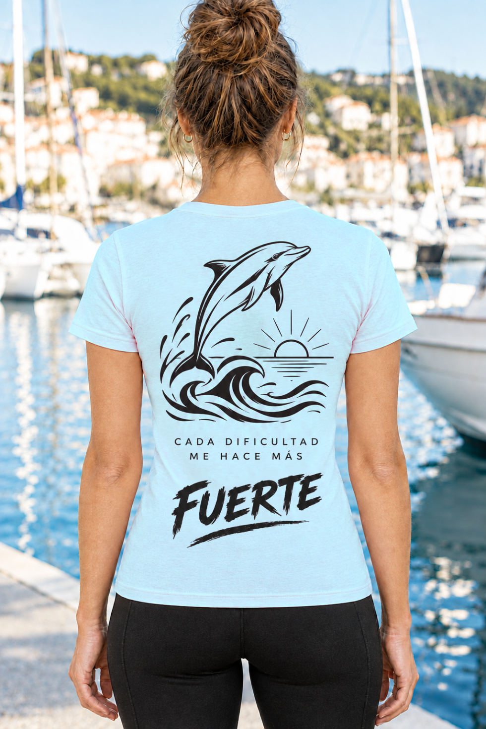 Vista trasera de camiseta azul cielo de mujer IMPARABL3 Sport Style, con ilustración negra de un delfín saltando sobre las olas y el mensaje «Cada dificultad me hace más fuerte».