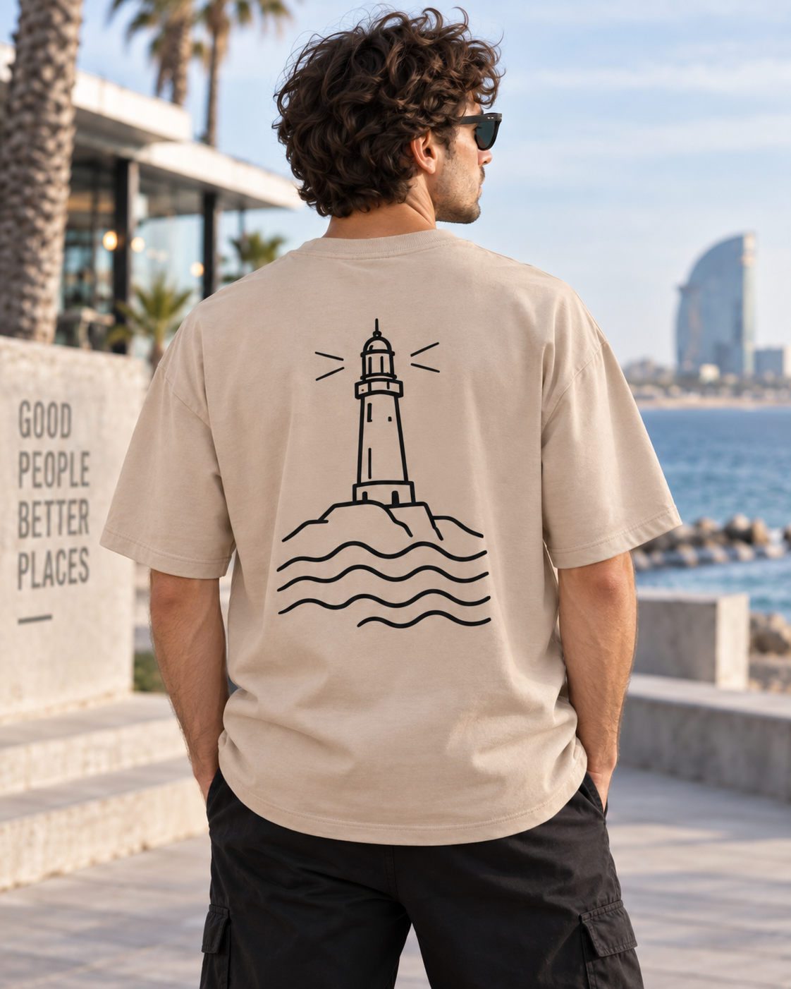 Vista trasera de la camiseta oversize de hombre de IMPARABL3 en color arena 07, con diseño minimalista de faro y olas