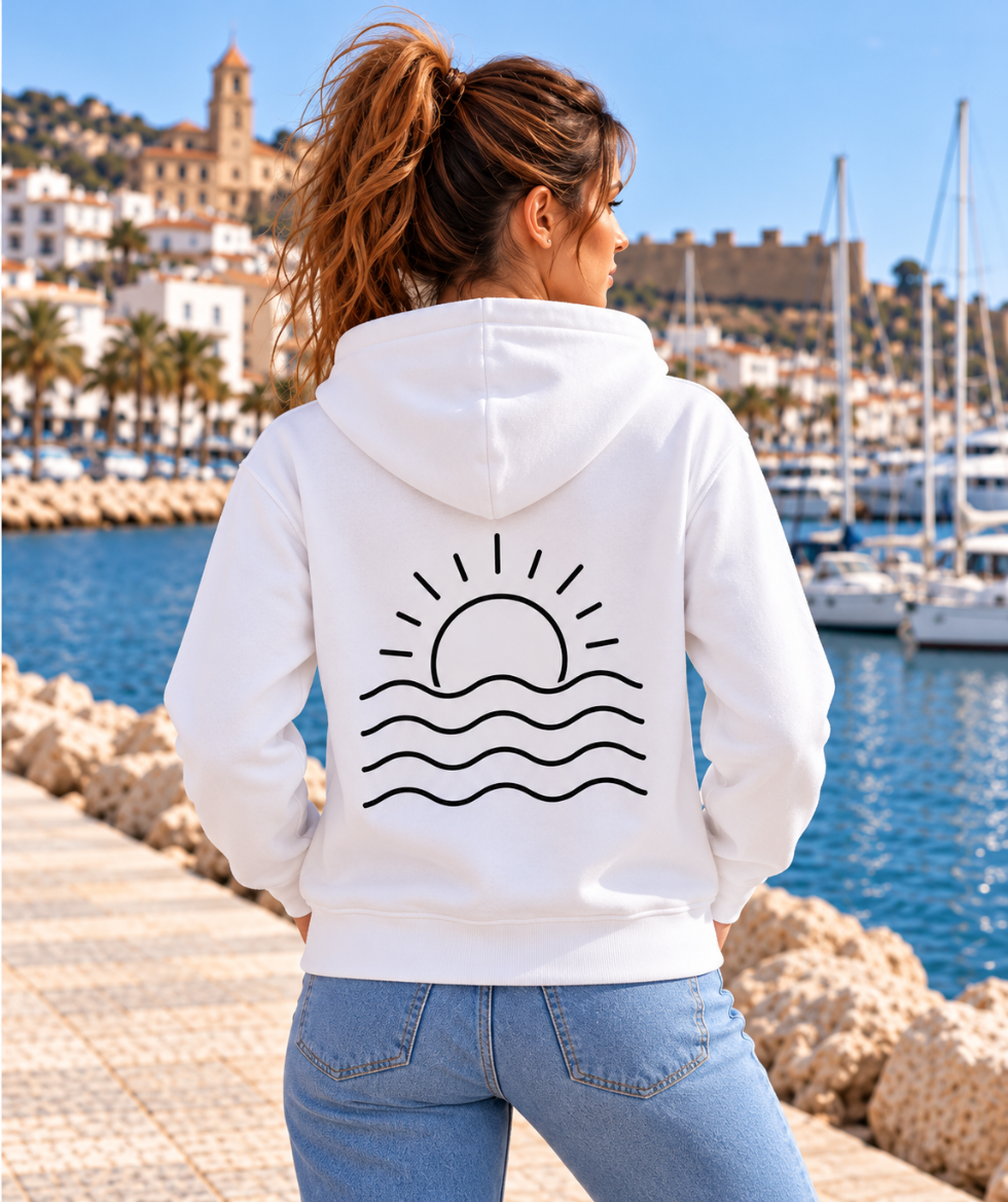 Vista trasera de la sudadera blanca ALBORADA de IMPARABL3, con capucha y diseño negro de un sol naciente sobre las olas del mar, en un puerto mediterráneo.