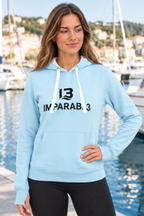 Mujer con sudadera celeste IMPARABL3 Sport Style, capucha con cordones blancos, bolsillo canguro, puños con abertura para pulgares y logotipo I3 IMPARABL3 negro centrado en el pecho.