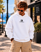 Modelo masculino con sudadera oversize blanca de IMPARABL3, con capucha, logotipo I3 negro centrado en el pecho y bolsillos laterales discretos.