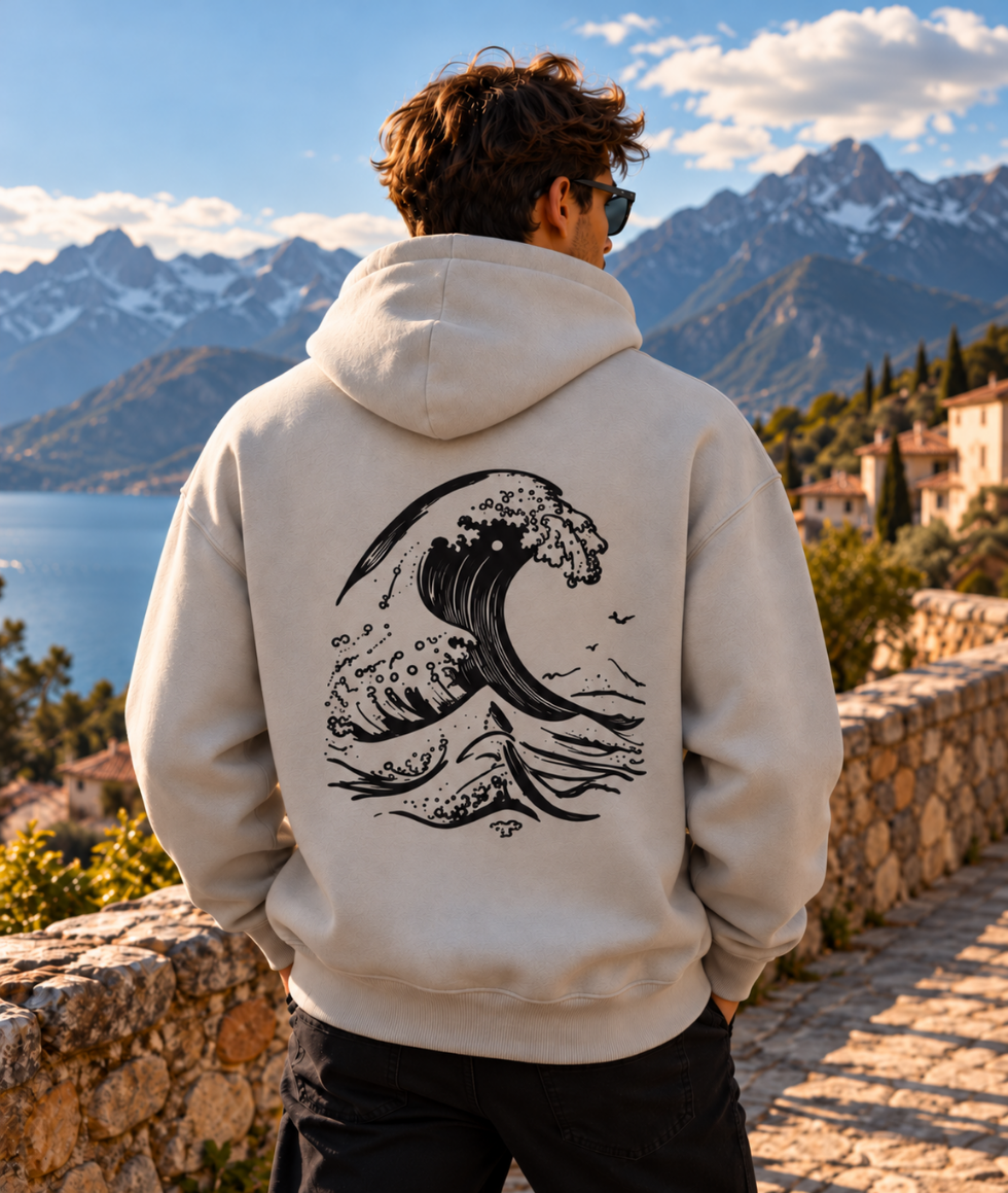 Hombre con sudadera oversize gris piedra de IMPARABL3, vista trasera con ilustración de ola japonesa negra estampada en la espalda.
